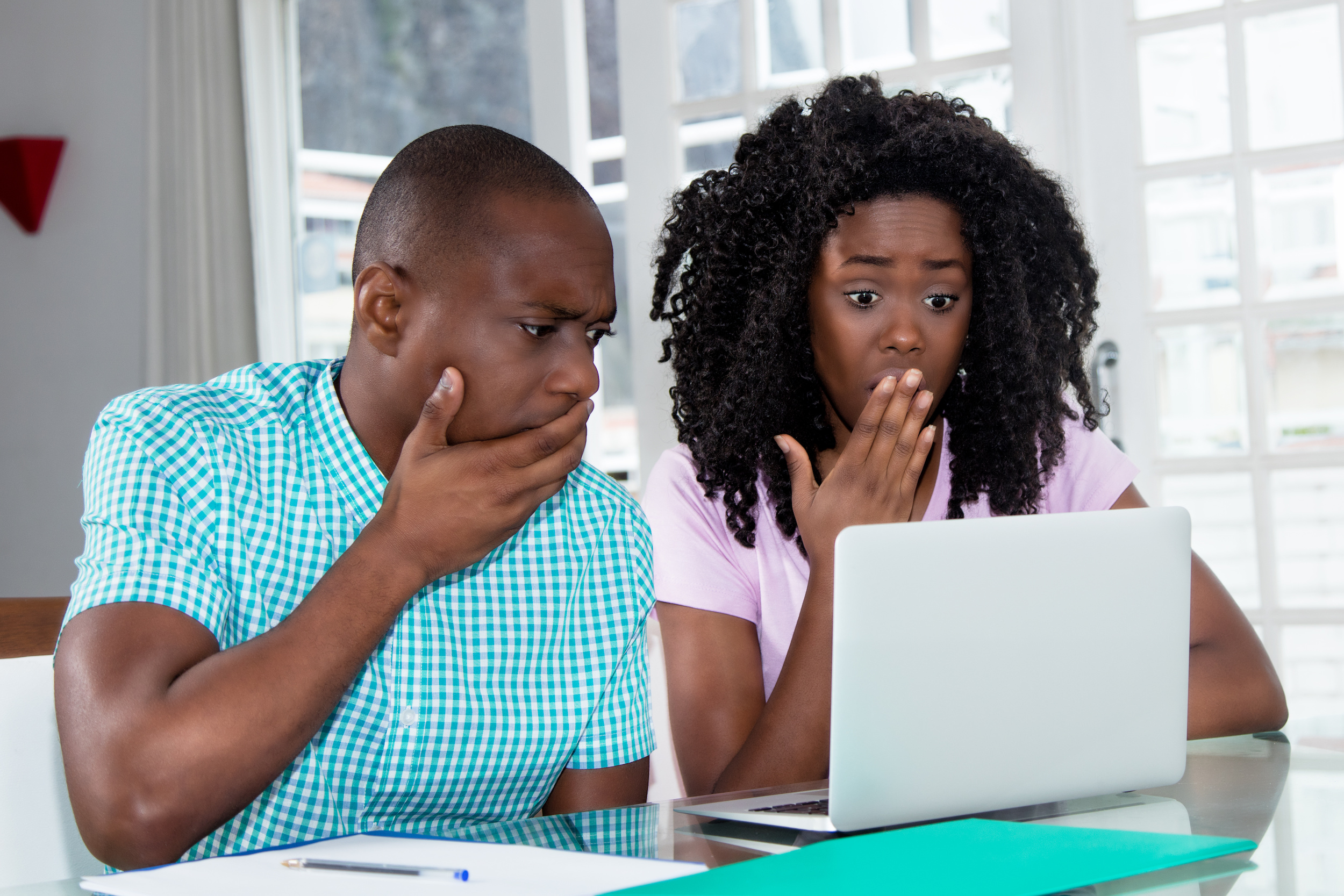 African american couple shocked about computer virus and identity theft at desk at home