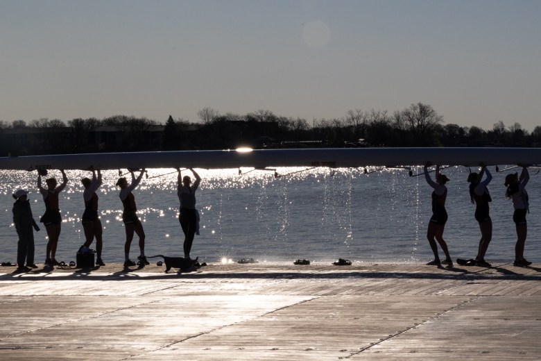 The rowing team carries the boat.