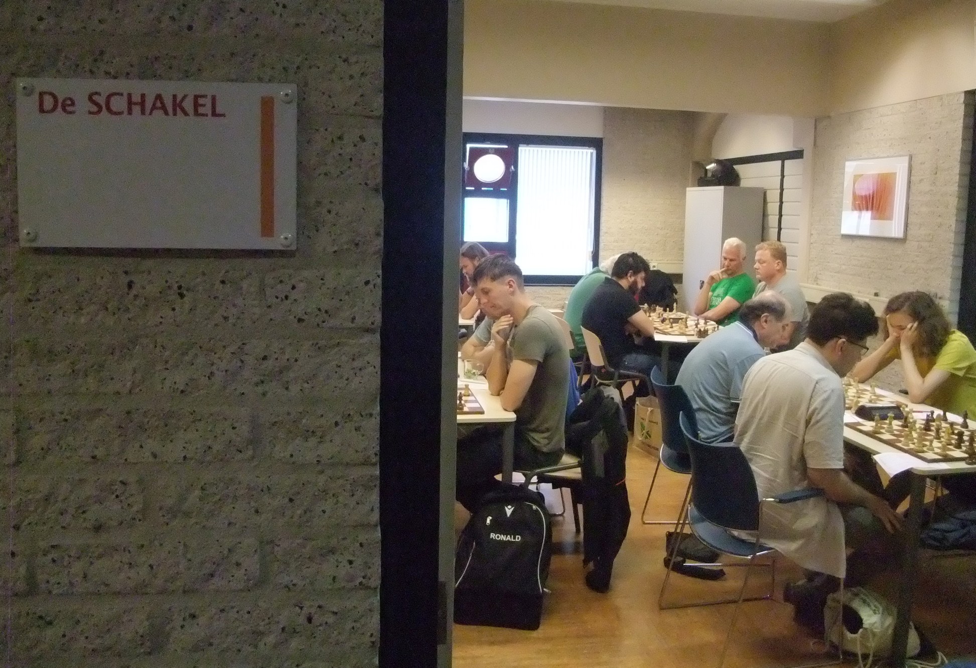 Deuropening zaal met wedstrijd van MDT 1 met naast de deur bordje 'De Schakel'