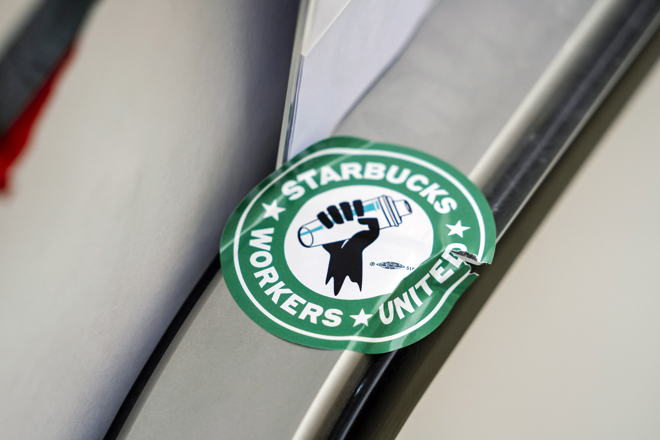 A Starbucks Workers United union sticker is seen outside the Starbucks Reserve Roastery and Tasting Room as employees picketed outside the storefront as part of nationwide strikes at Starbucks locations in Seattle, Washington, USA, on Fri., Dec. 20, 2024. The Roastery is one of five unionized Seattle locations on strike today, the first of a five day strike by Starbucks employees. The workers chanted "No Contract, No Coffee," and made complaints about the 1.5% year-end raise they received.