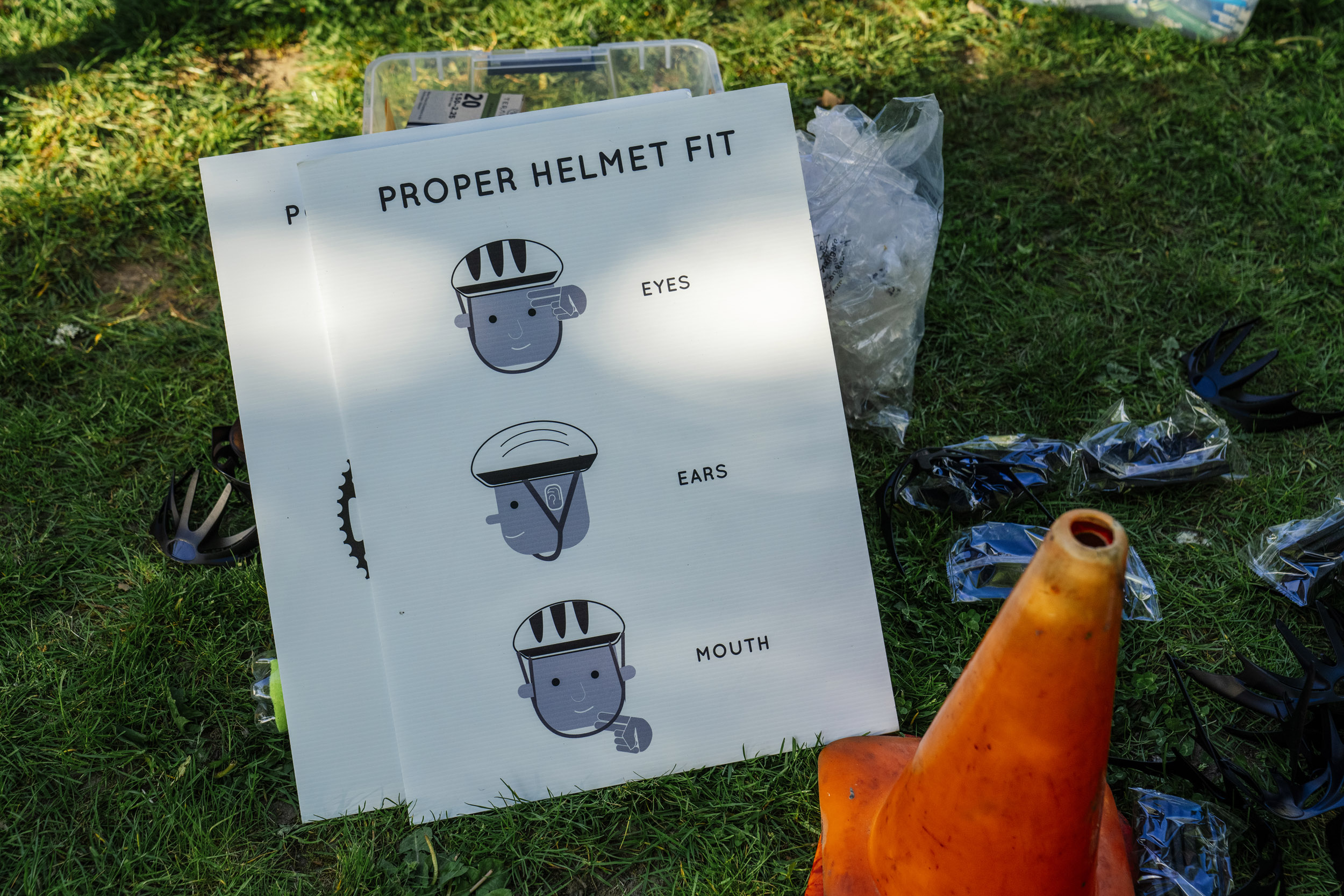 A sign indicates the proper methods of fitting a bicycle helmet as Pedal Forward Shoreline participants during an e-bike-focused urban cycling class at Ridgecrest Elementary School in Shoreline, Washington, USA, on Wed., May 7, 2025. Pedal Forward Shoreline is a program to give free e-bikes to residents in what has been deemed an “overburdened community” determined to have health, social, and environmental inequities at the south end of Shoreline east of I-5. As part of an effort to reduce driving in the city, the program will give out approximately 100 e-bikes to residents in the neighborhood, prioritizing households with incomes at or below 80% of the King County median income.   (M. Scott Brauer / Cascade PBS)