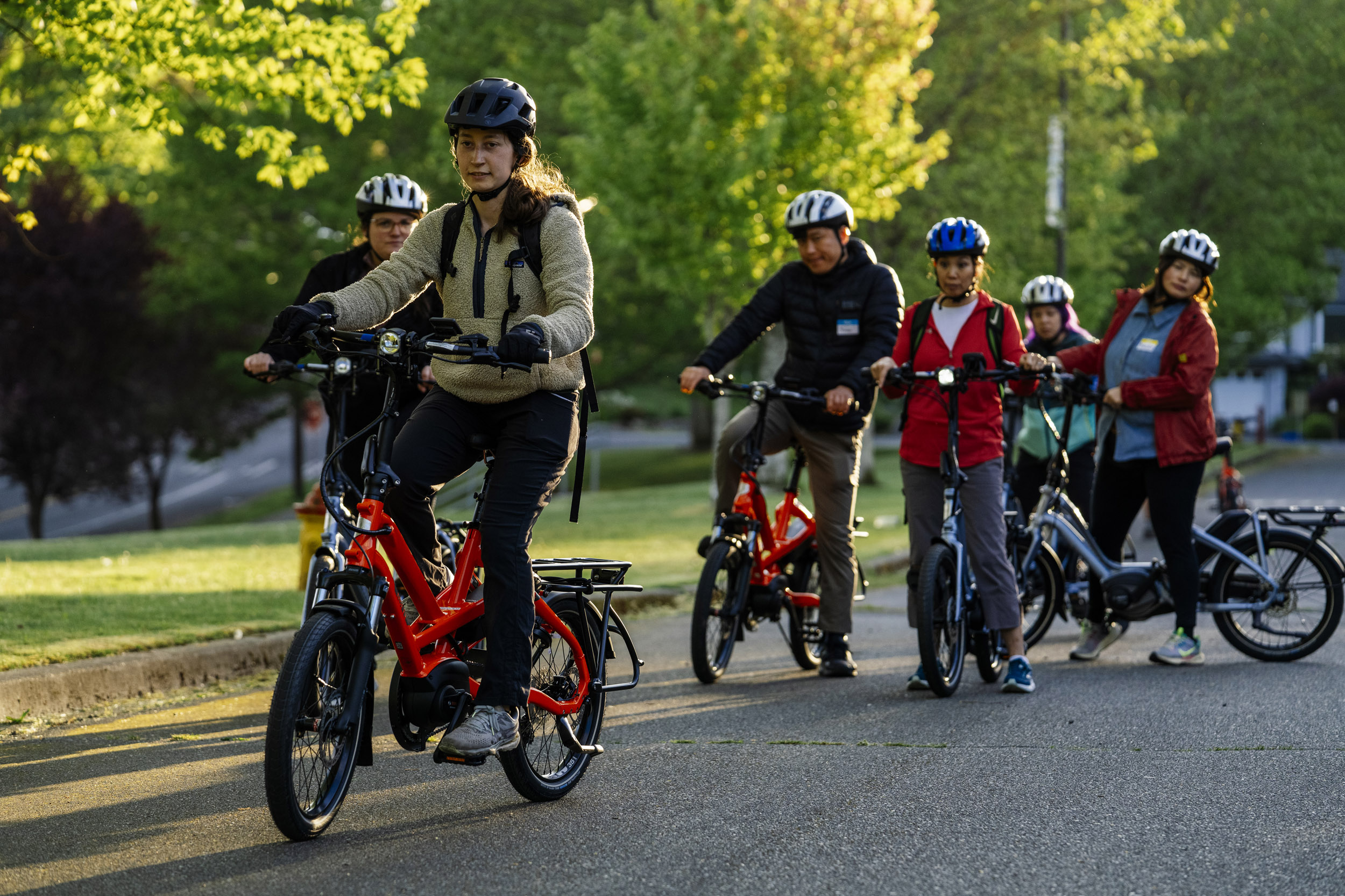 Lily Sheets (foreground), instructor with Cascade Bicycle Club, leads Pedal Forward Shoreline participants during an e-bike-focused urban cycling class at Ridgecrest Elementary School in Shoreline, Washington, USA, on Wed., May 7, 2025. Pedal Forward Shoreline is a program to give free e-bikes to residents in what has been deemed an “overburdened community” determined to have health, social, and environmental inequities at the south end of Shoreline east of I-5. As part of an effort to reduce driving in the city, the program will give out approximately 100 e-bikes to residents in the neighborhood, prioritizing households with incomes at or below 80% of the King County median income.   (M. Scott Brauer / Cascade PBS)