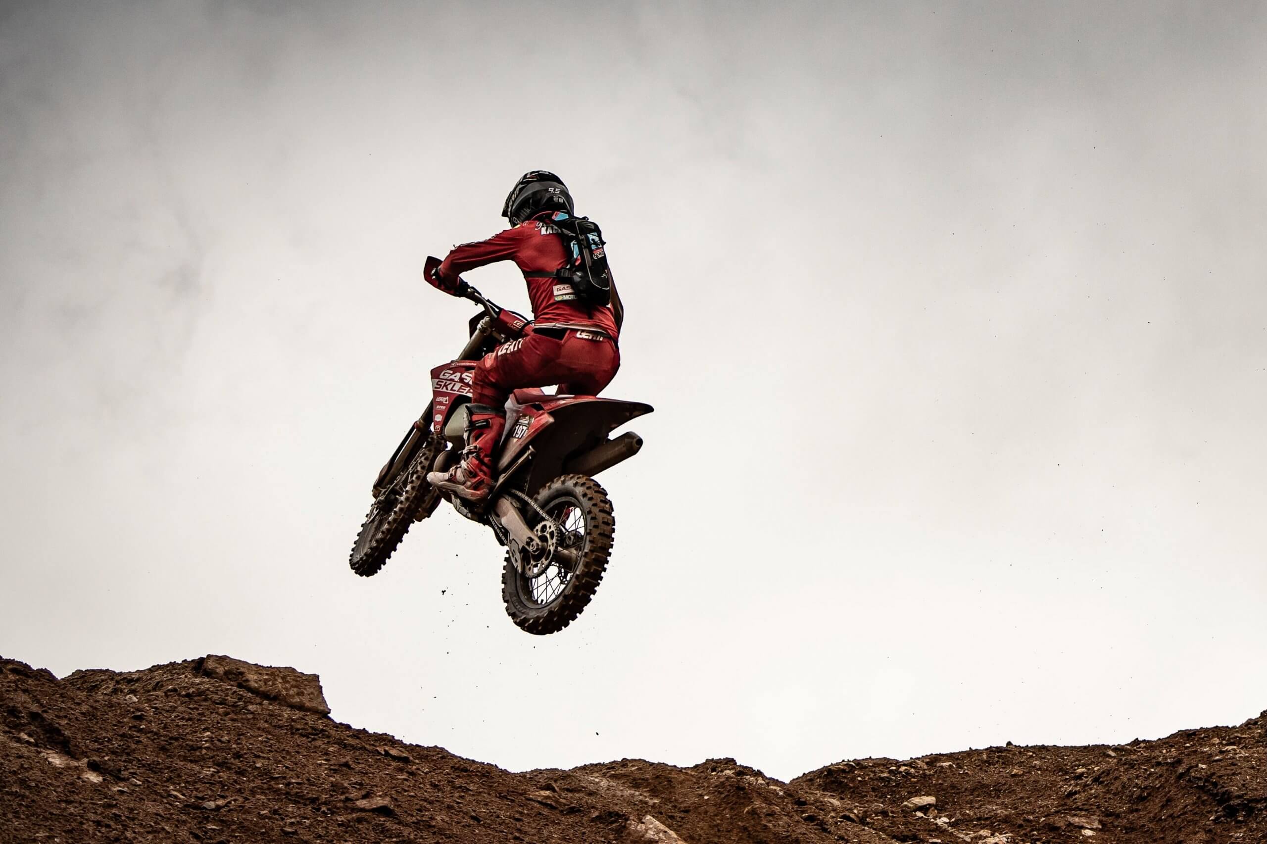 Ein Motorrad das mit dem / der Fahrer:in gerade in der Luft ist am oberen Ende einer "Rampe".