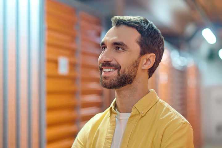 Joyful man lookin up and to side in a yellow shirt