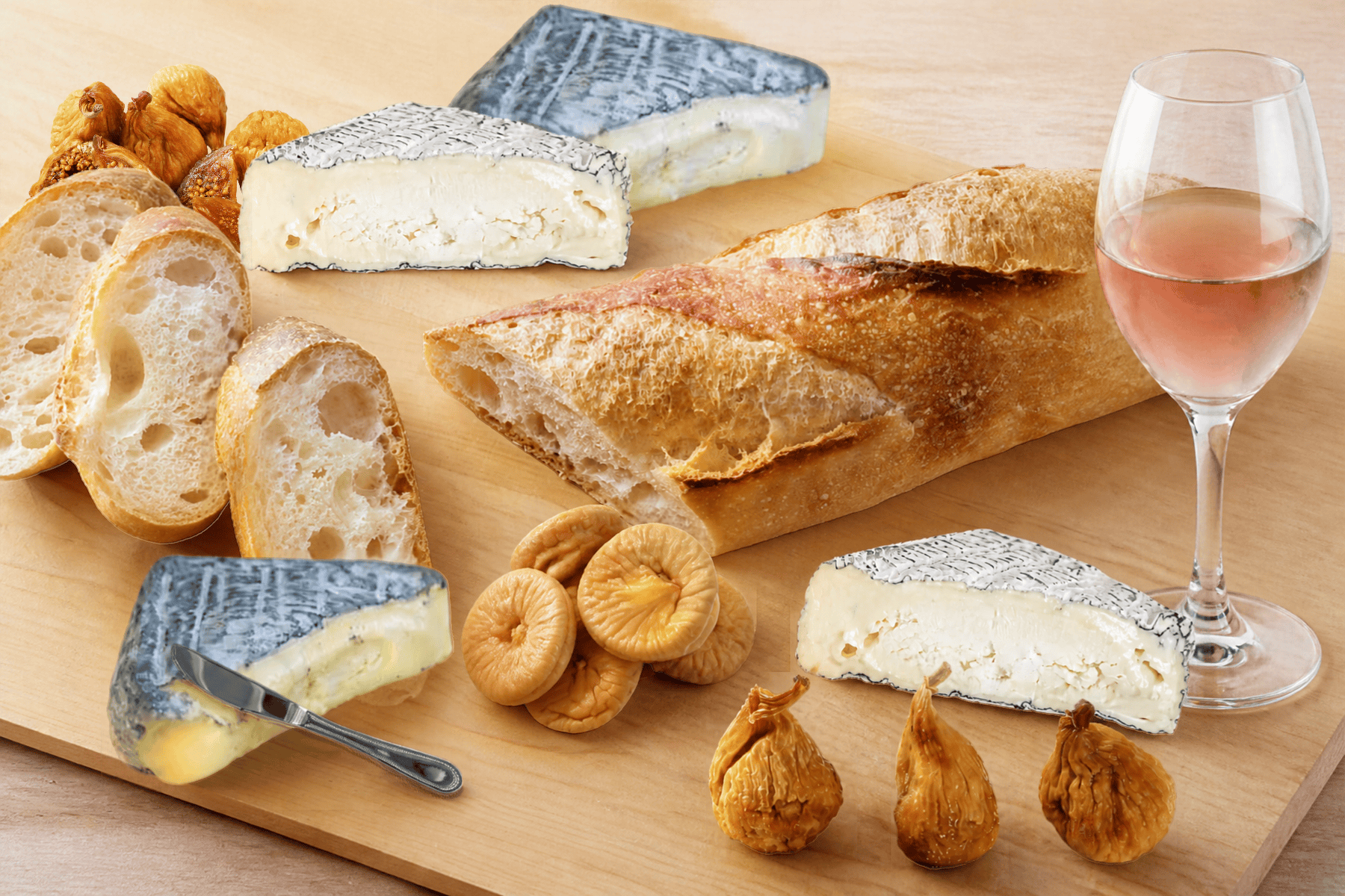 A cut square of Boxcarr Rocket's Robiola with figs, bread and rosé on a wooden board