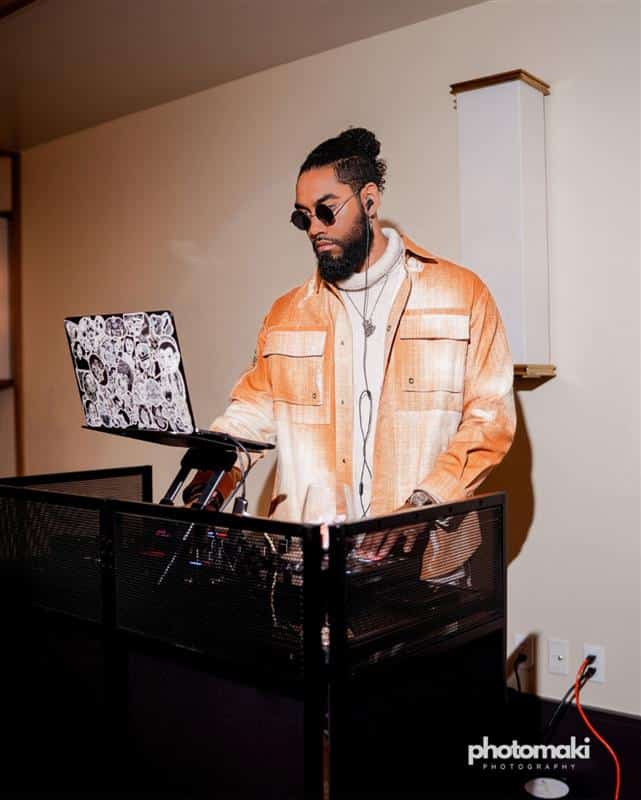 A DJ standing at a desk with a laptop