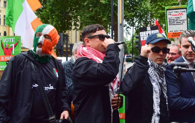 Moglai Bap gives a speech alongside Kneecap bandmates DJ Provai (l) and Mo Chara (r) outside Westminster Magistrates Court during the demonstration in support of Mo Chara (Photo by Vuk Valcic/SOPA Images/LightRocket via Getty Images)