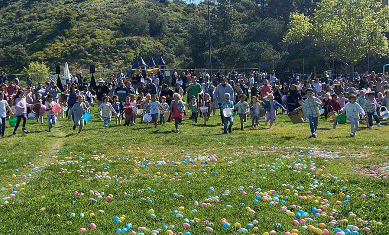 A crowd of children heads toward a grass field strewn with pastel-colored Easter eggs. (Courtesy photo)