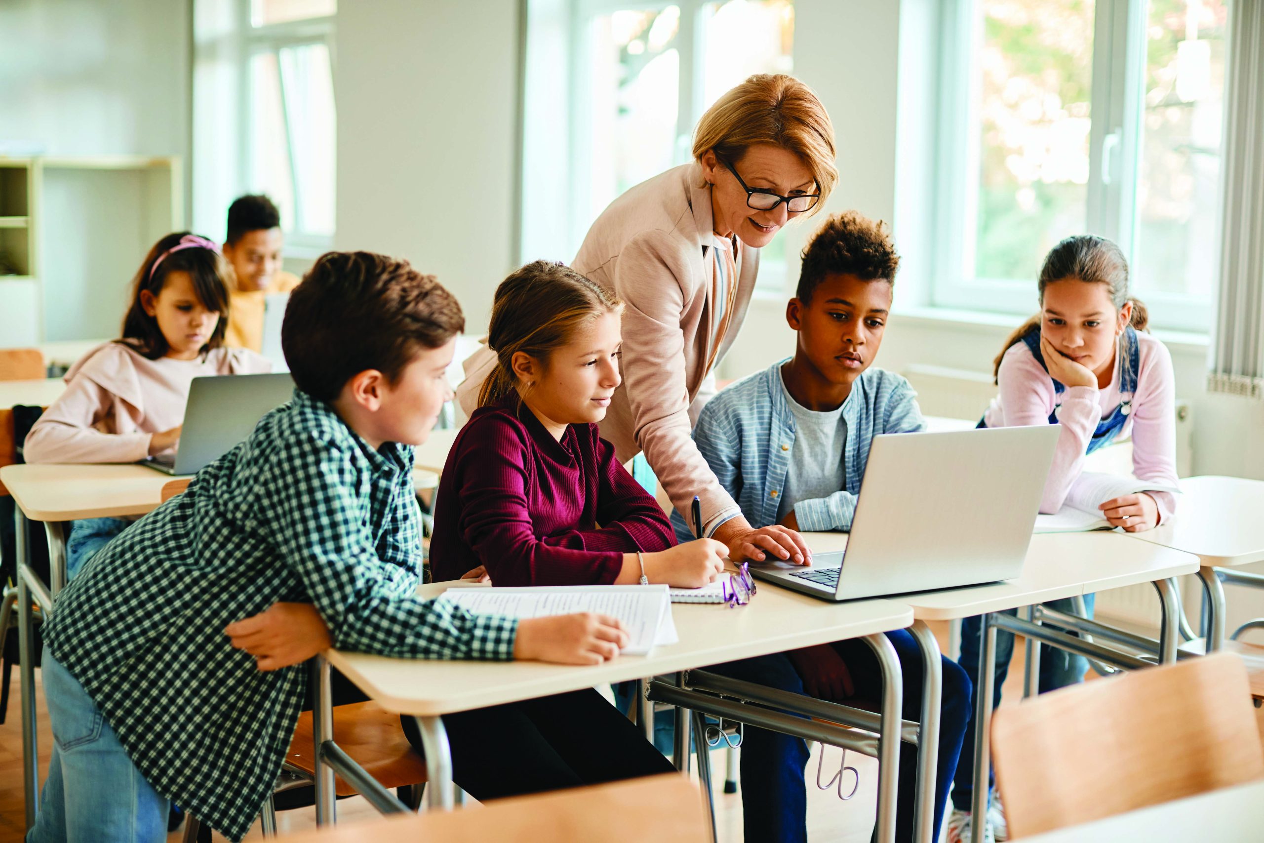Teacher in a class showing teaching her using a laptop