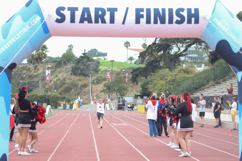 SBCC Superintendent/President Erika Endrijonas raises her arms in victory as she crosses the finish line in the Vaquero 5k. (Courtesy photo)