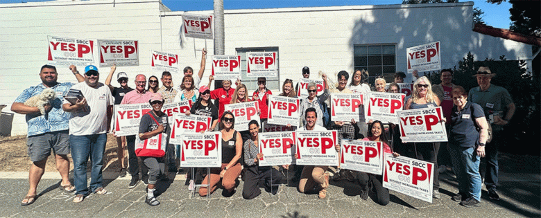 Measure P proponents hold up red and white 'Yes on P' signs. (Courtesy photo)