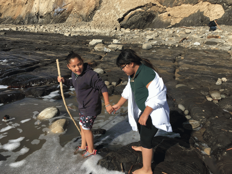 Young participants in the Wilderness Youth Project hold hands as they walk across a stream. (Courtesy photo)