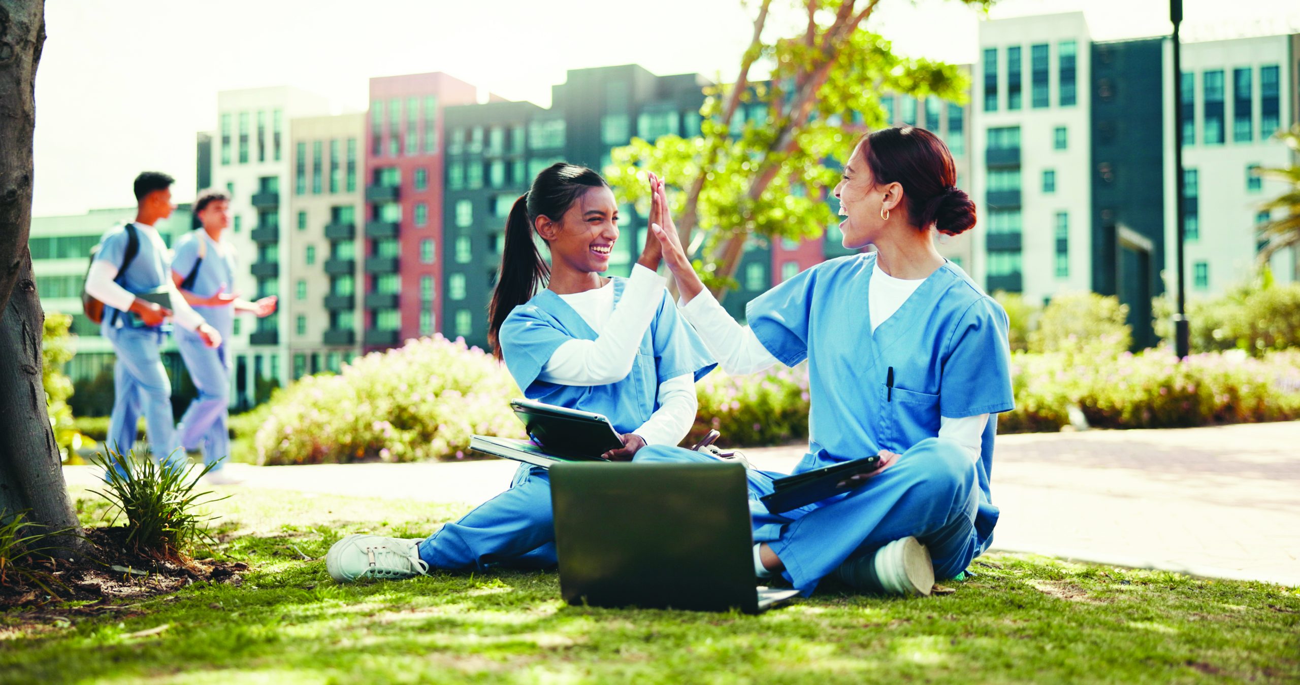 Women nurses high five with laptop for internship.