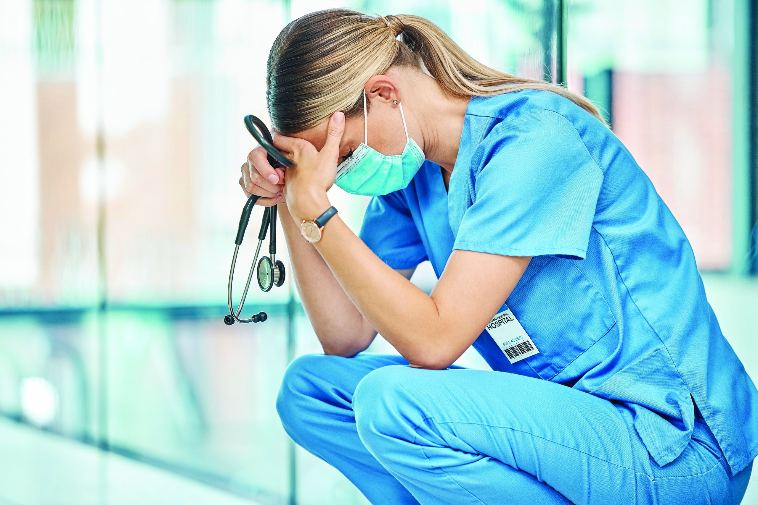 Nurse experiencing burnout in a healthcare clinic with stethoscope.