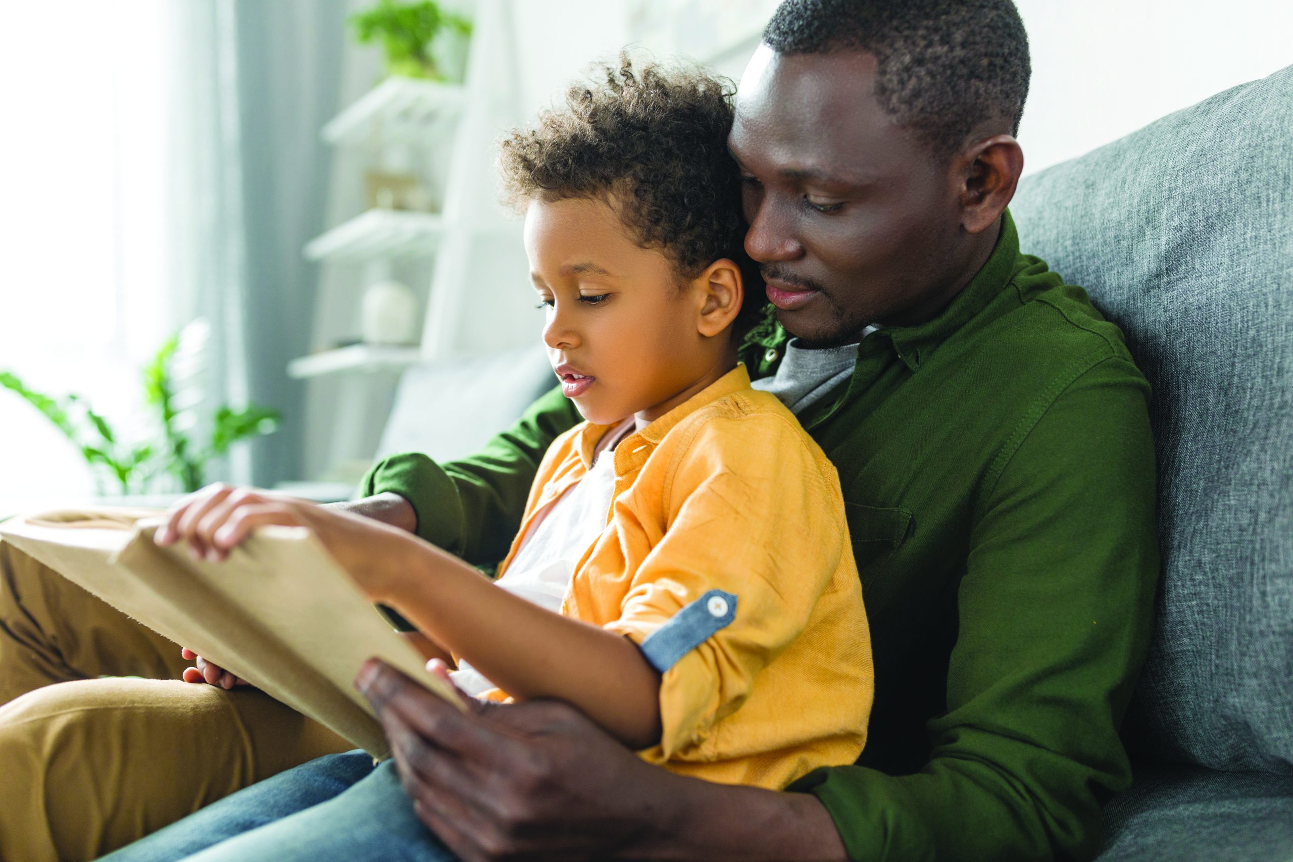 father and son reading book together