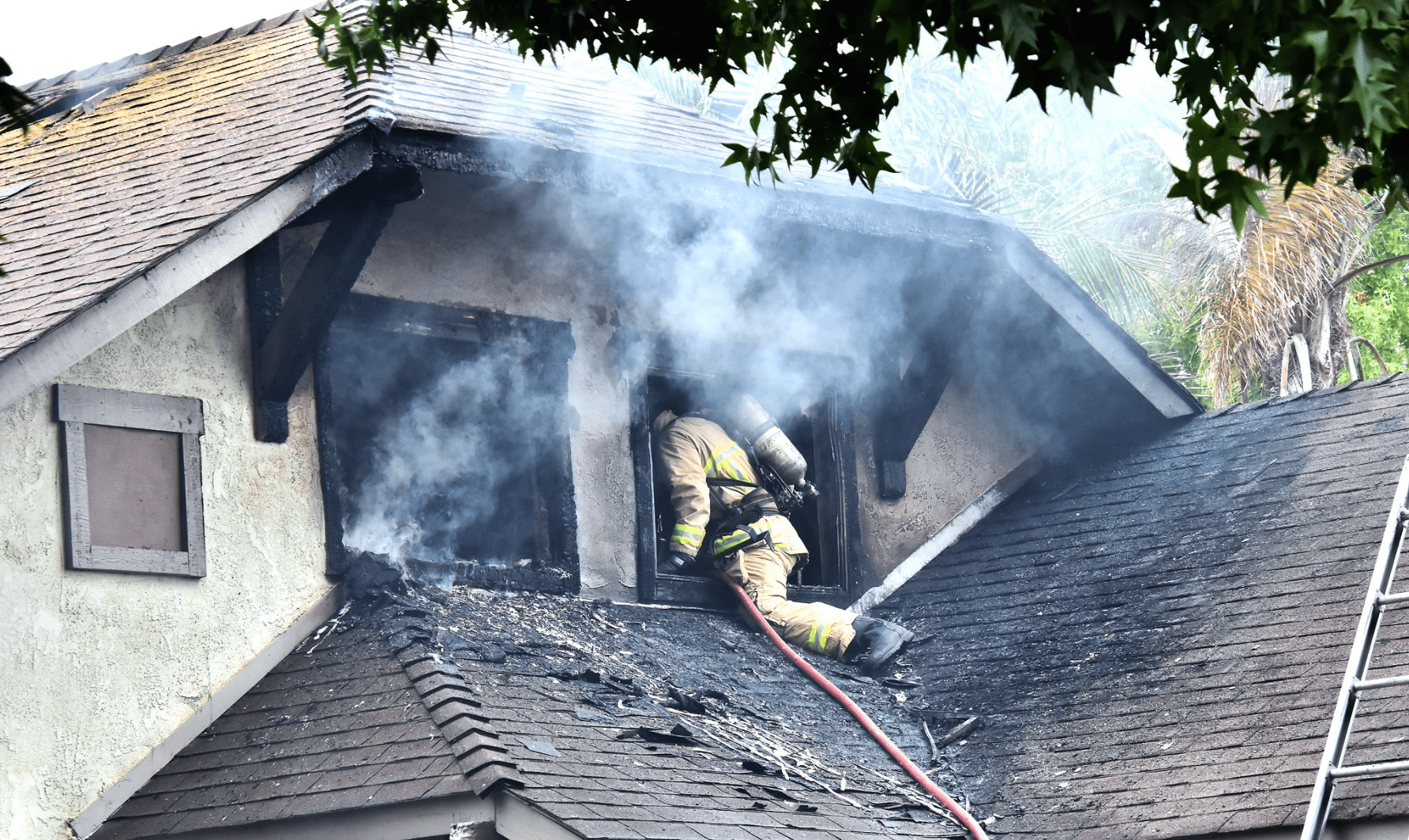 A firefighter climbs through the window of a home on fire in Santa Maria Monday morning. Two people were injured in the blaze.