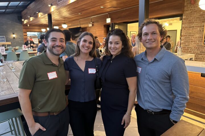 Four attendees with name badges pose together in the bar area at Midwest Coast Brewing