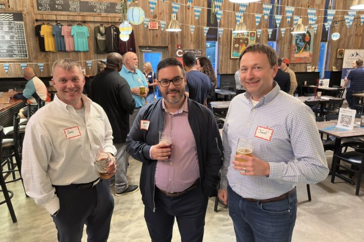 Three attendees with name badges raise beers in the Riverlands Brewing taproom in St. Charles