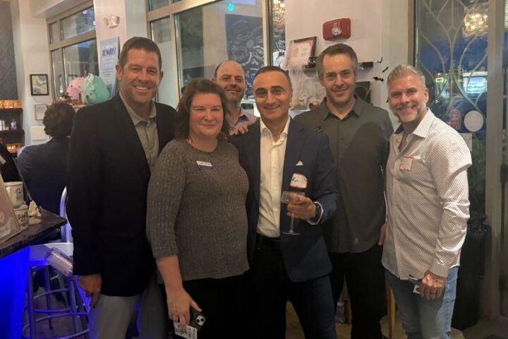 Six attendees with name badges pose together near the bar at CoCo & Blu in Arlington Heights