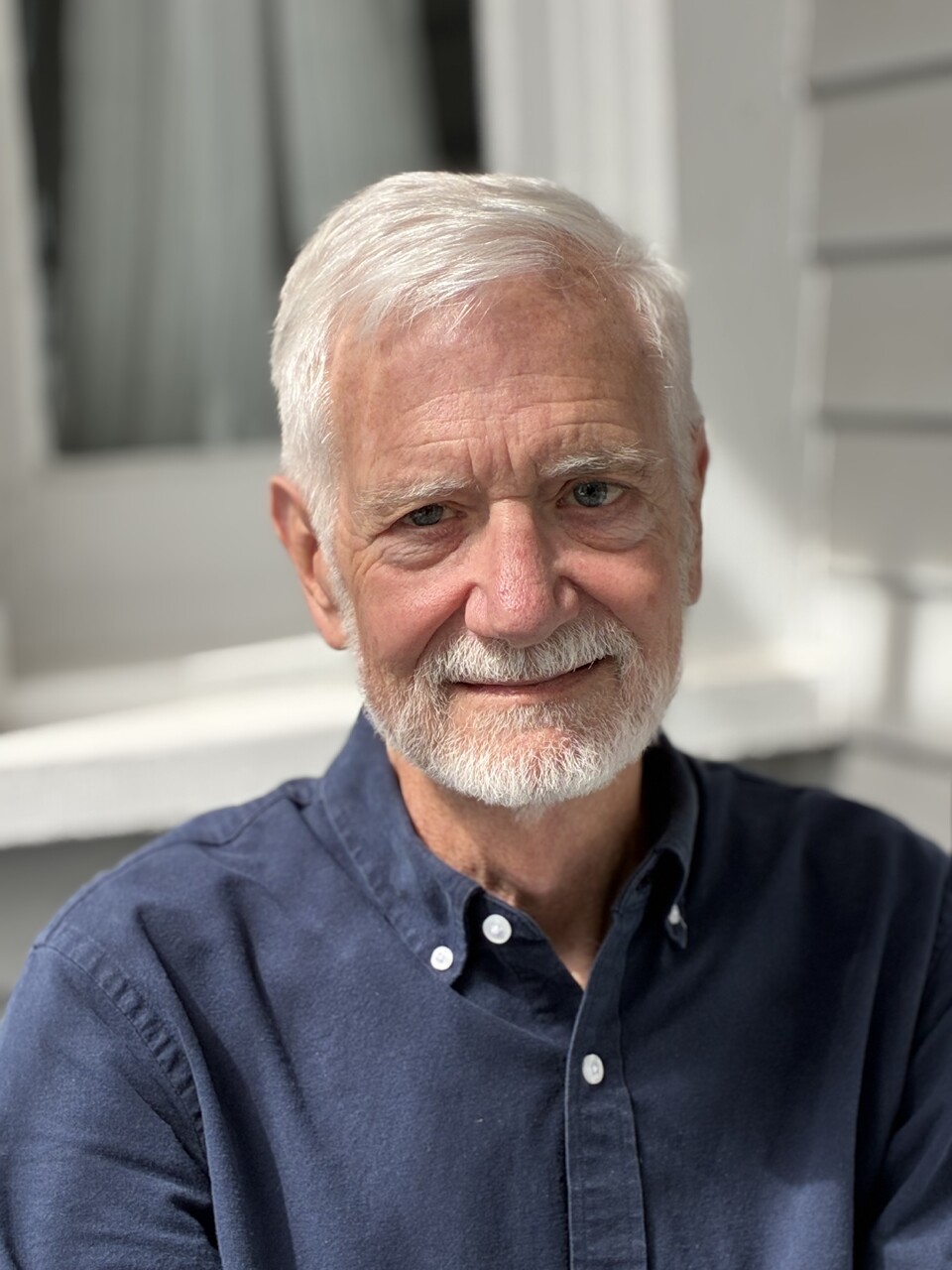 Jim Farrell poses for a selfie smiling at the camera in a dark blue button down shirt.