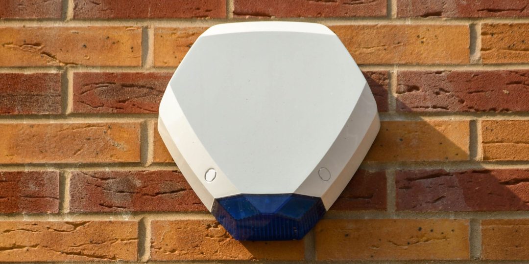Intruder Alarms white external burglar alarm siren mounted on brick wall for home security