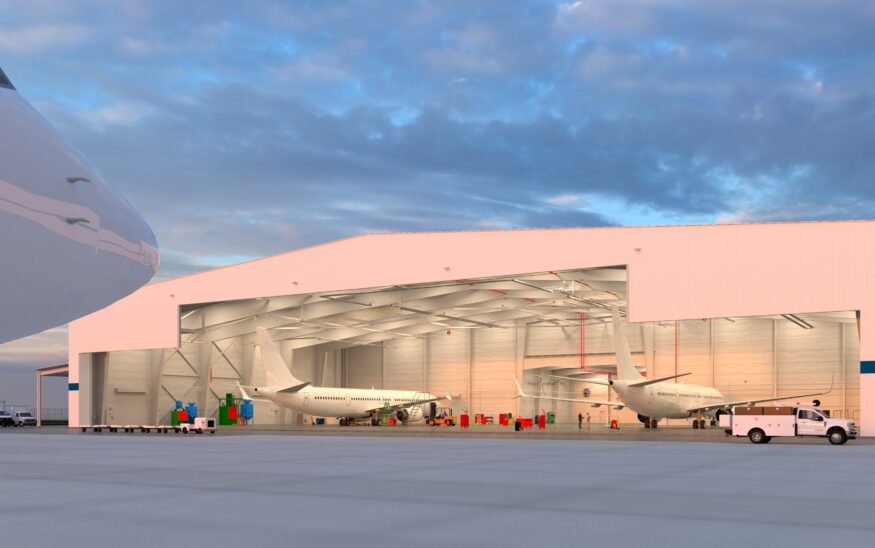 Wide exterior shot of a pink airplane hangar with two planes inside with clouds and gray sky above.