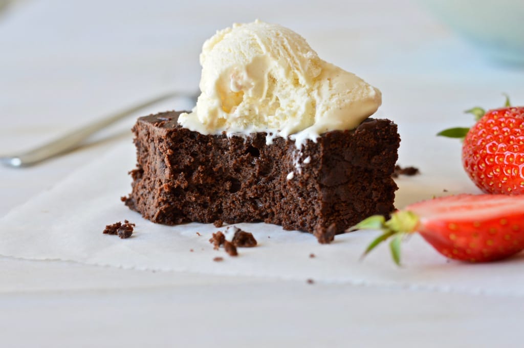 Close-up of fudgy Black Bean Brownies, cut into squares, with a slightly cracked top and visible dark chocolate chunks, served on a plate.