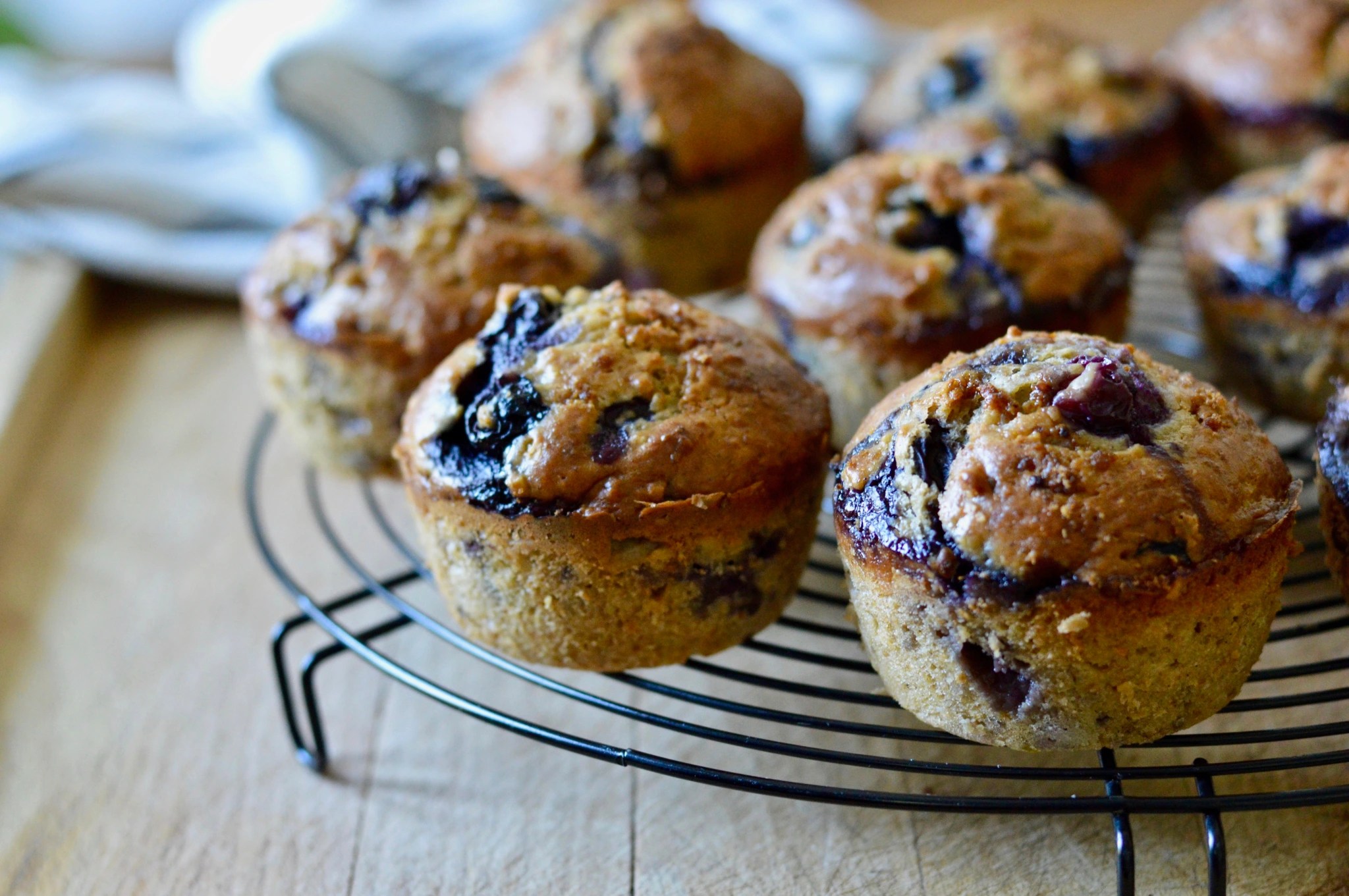 Close-up of golden-brown vegan blueberry muffins, some with a sprinkle of sugar on top, showcasing plump blueberries and a wholesome texture.