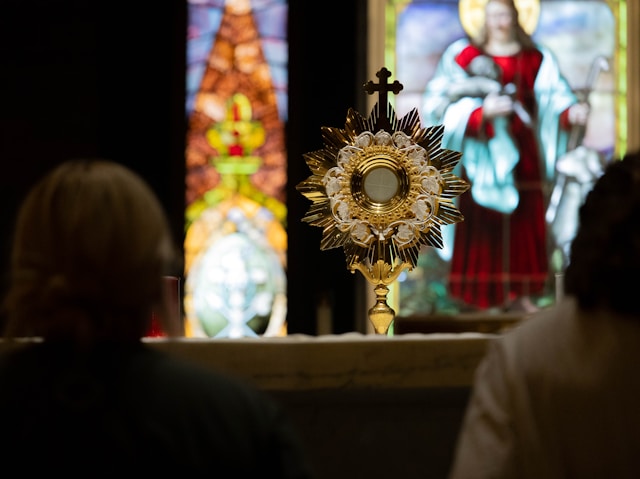 Two people adoring the Blessed Sacrament in a Catholic Church