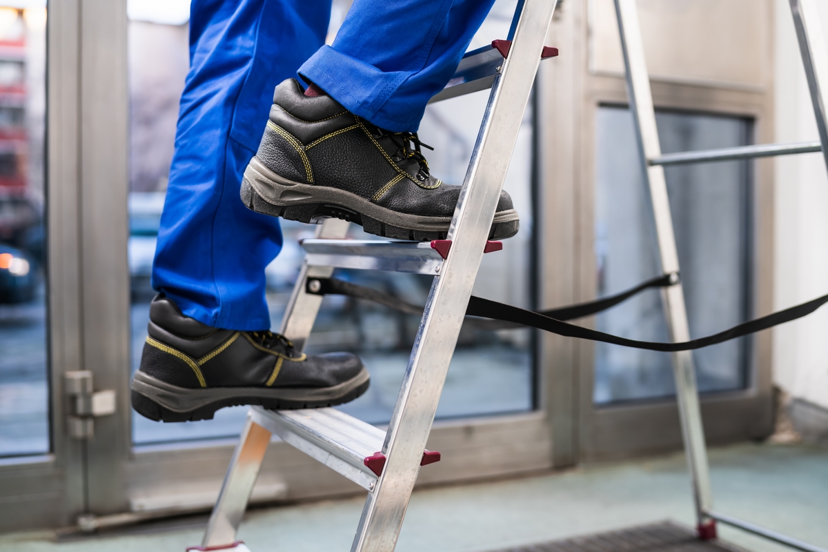 Low Section View Of A Handyman's Foot Climbing Ladder