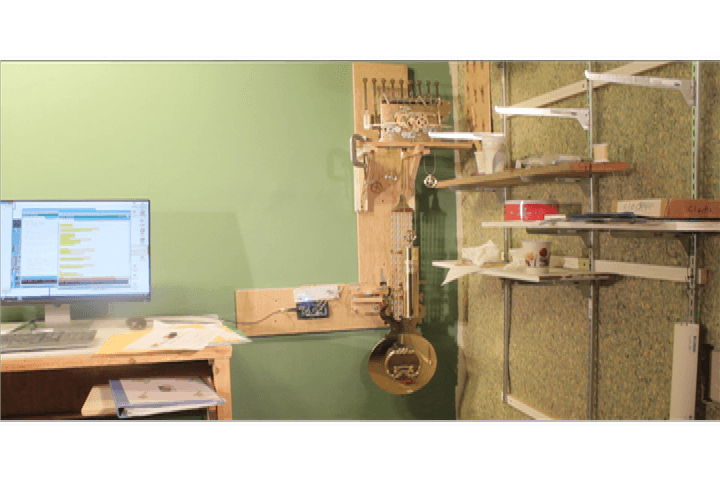 Large wood jig wioth grandfather clock and Arduino with wires attached to wall.
