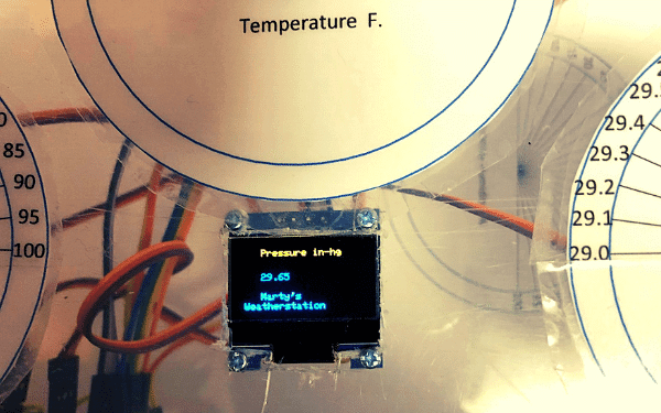 small OLED display with wires in background showing barometric pressure
