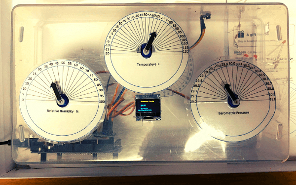 a case with 3 analog displays for temperature, pressure and humidity. An OLED display with the same but digital, arduino mega with wires in background of case
