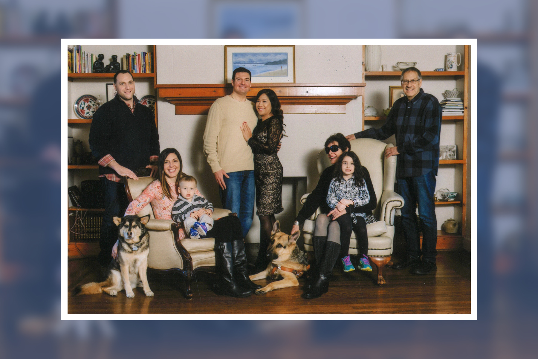 Essay author Sally Hobart Alexander sits in a chair holding granddaughter Raya Greenberg. Standing next to her is her husband, Bob and their children, grandchildren and dogs. Joel and Vannida Alexander stands in the center; Jeremy and Leslie Greenberg, holding Clyde, are to the left; with dogs Sabrina and Dave.