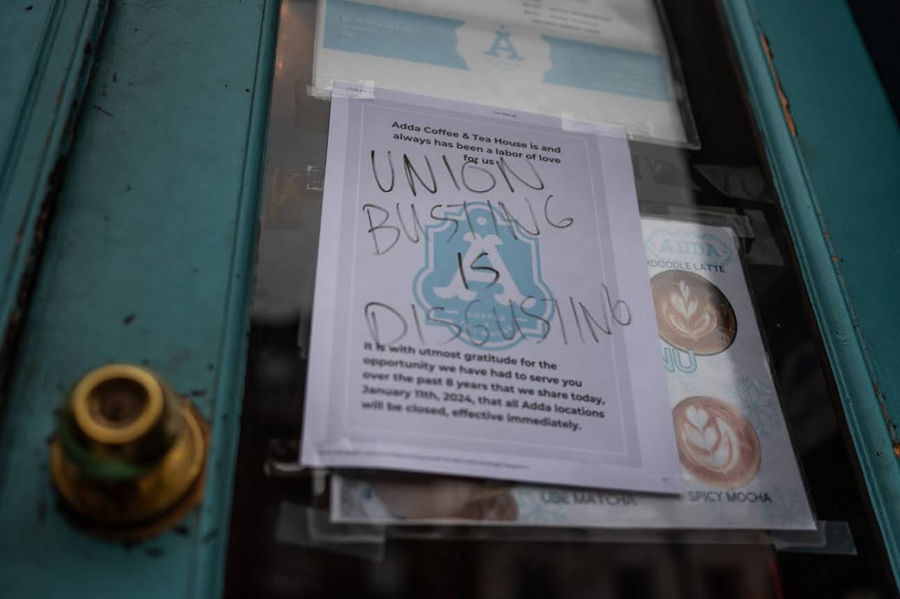 handwritten writing covers over a printed paper sign on a shop door.