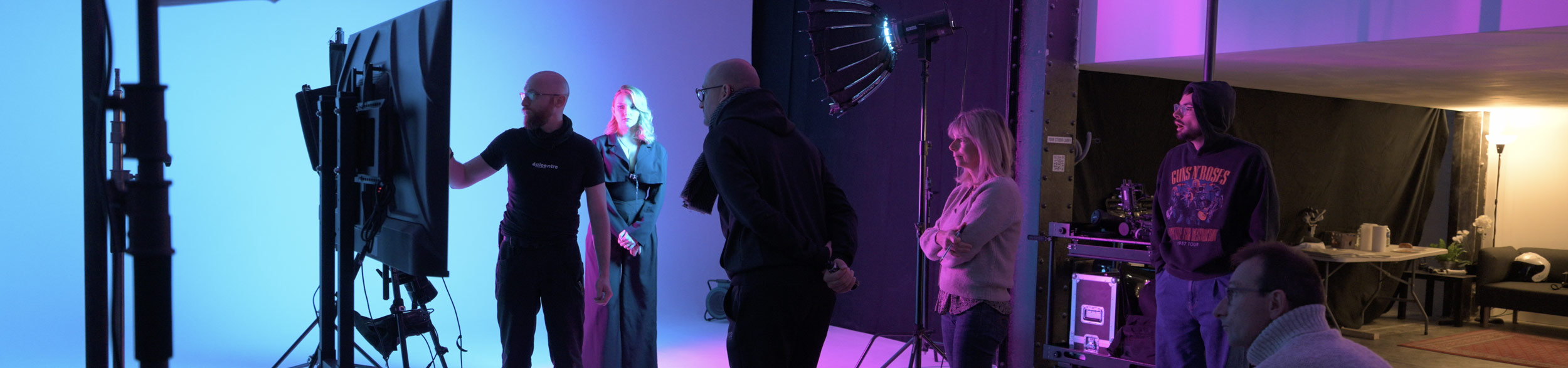 Équipe de tournage réunie autour d’un moniteur, avec caméras et projecteurs en studio