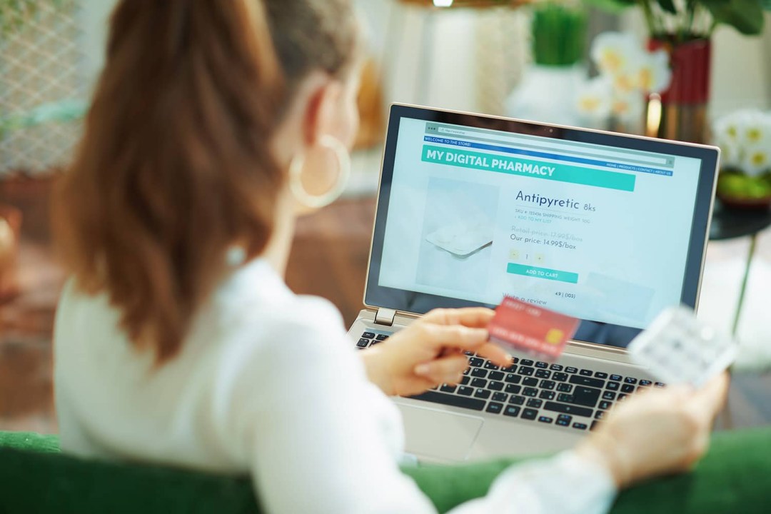 Photograph of a woman purchasing from a pharmacy ecommerce website using a credit card Photograph of a woman purchasing from a pharmacy ecommerce website using a credit card