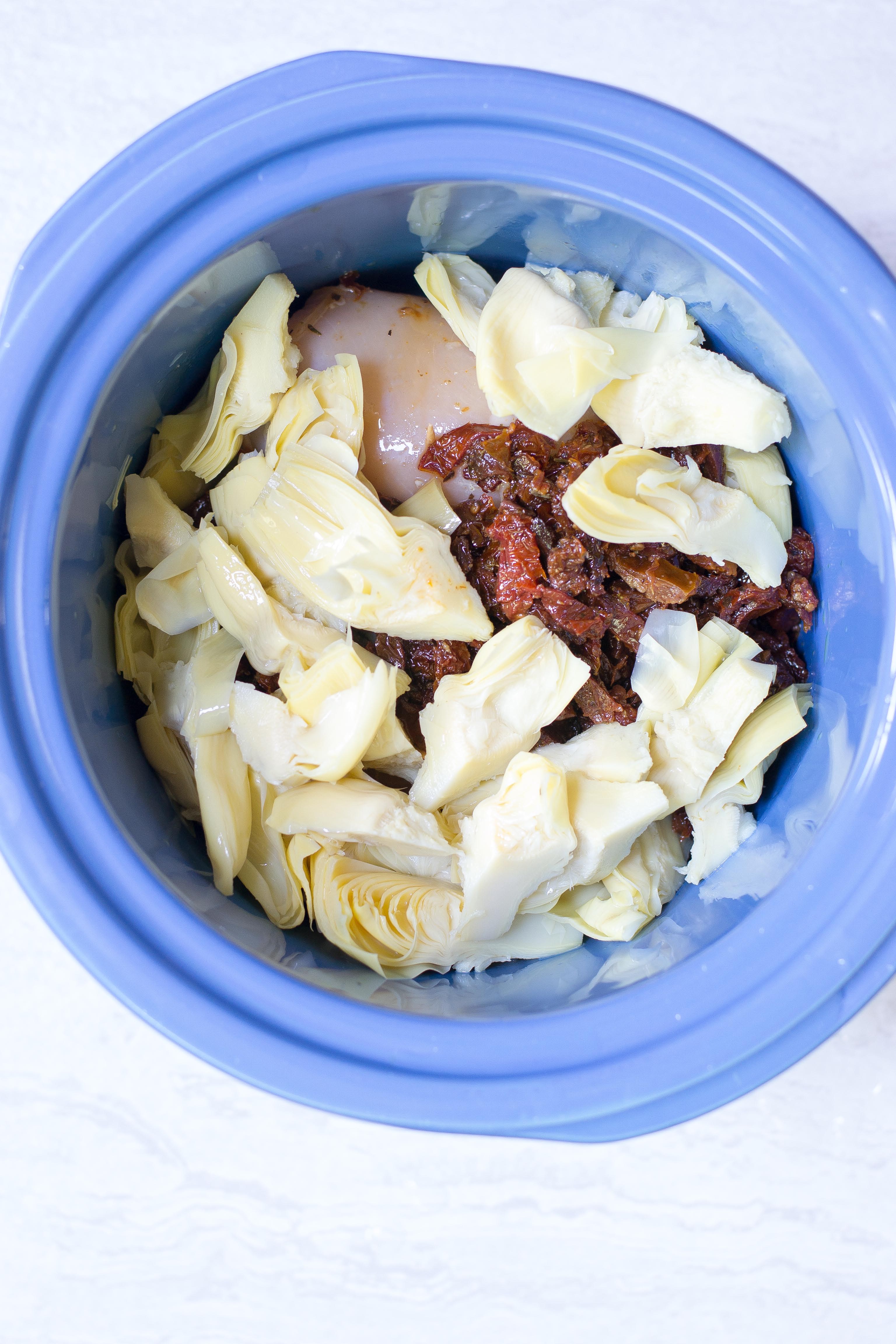 Slow Cooker Mozzarella Stuffed Chicken Breasts – Mozzarella stuffed chicken breasts are smothered with sun-dried tomatoes and artichoke hearts and slow cooked to perfection. Easy and delicious. A great meal for entertaining. Gluten-free. | QueenofMyKitchen.com