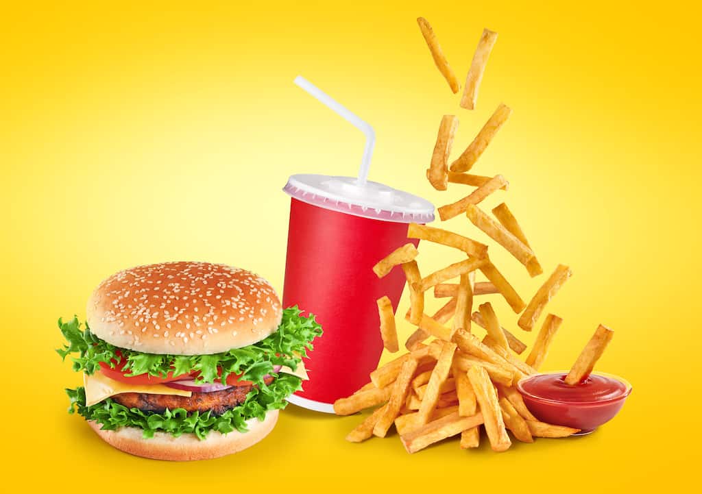 A man holding a burger from a fast food restaurant. Fast Food Restaurants Recycling Solutions Waste Less Pay Less