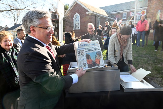 David Patti holds up a copy of the Reading Times from Dec. 31, 1998, during a ceremony on Saturday to reveal the contents of Reading's 250th Anniversary time capsule at the Berks History Center. (BILL UHRICH - READING EAGLE)