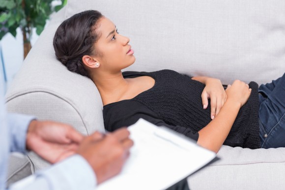 woman-talking-during-therapy-session-while-therapist-takes-notes