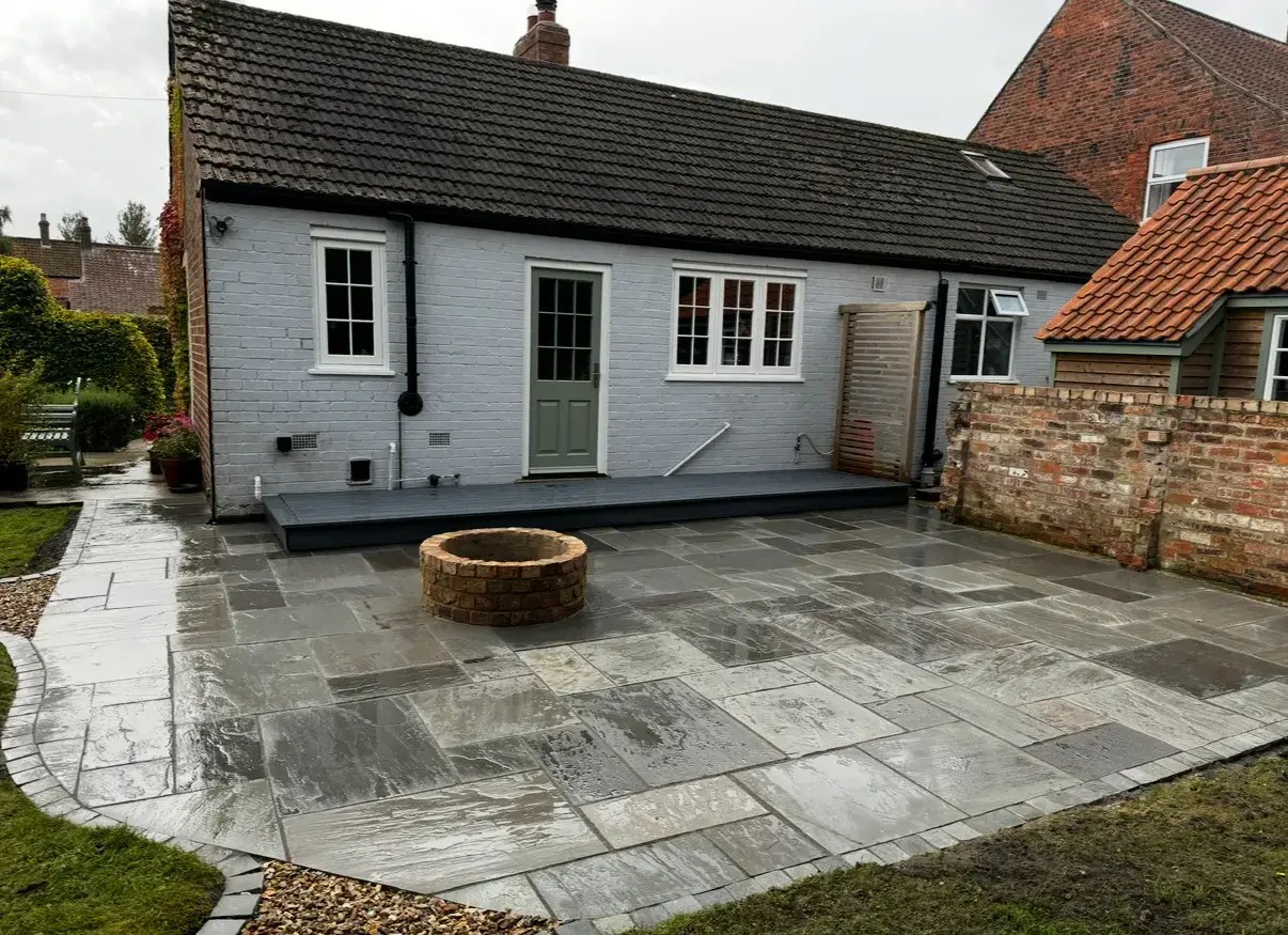 Patio installation in Lincoln with grey sandstone paving curved border and brick firepit