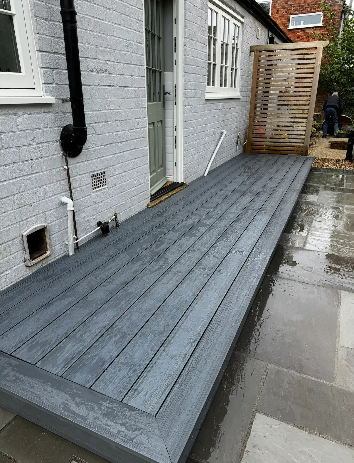 Decking installation in Lincoln with grey composite boards beside sandstone patio and timber screen