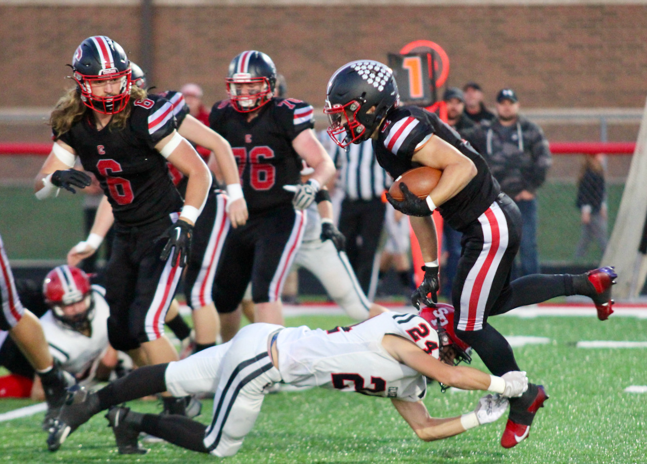 A football player dives to tackle the ball carrier