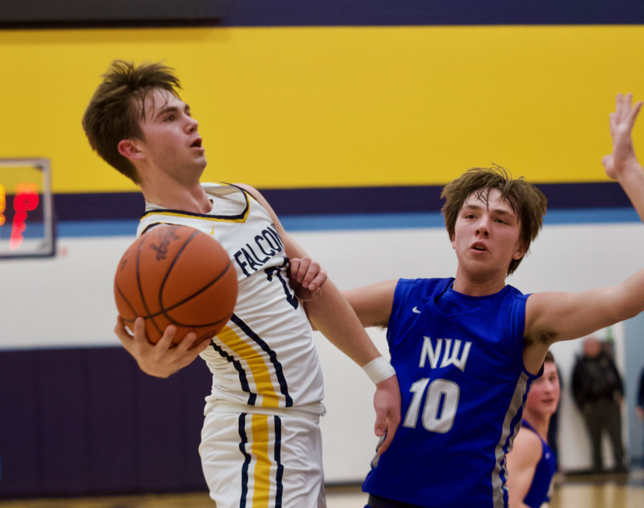 a basketball player drives to the basket against a defender