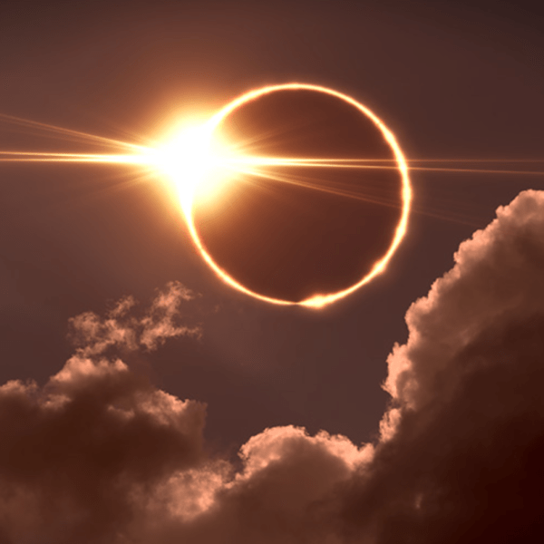 A solar eclipse showing a dark sky and a ray of sunlight on the right of the moon's shadow.