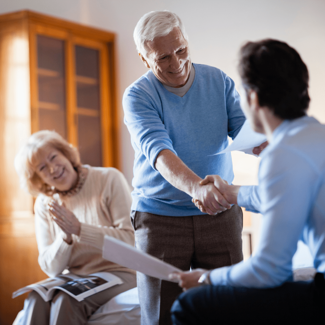 a senior couple speaks with a representative, the man shakes his hand with a smile. For the neighbourhood referral deal.