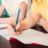 child's hand writing on a paper with a pencil