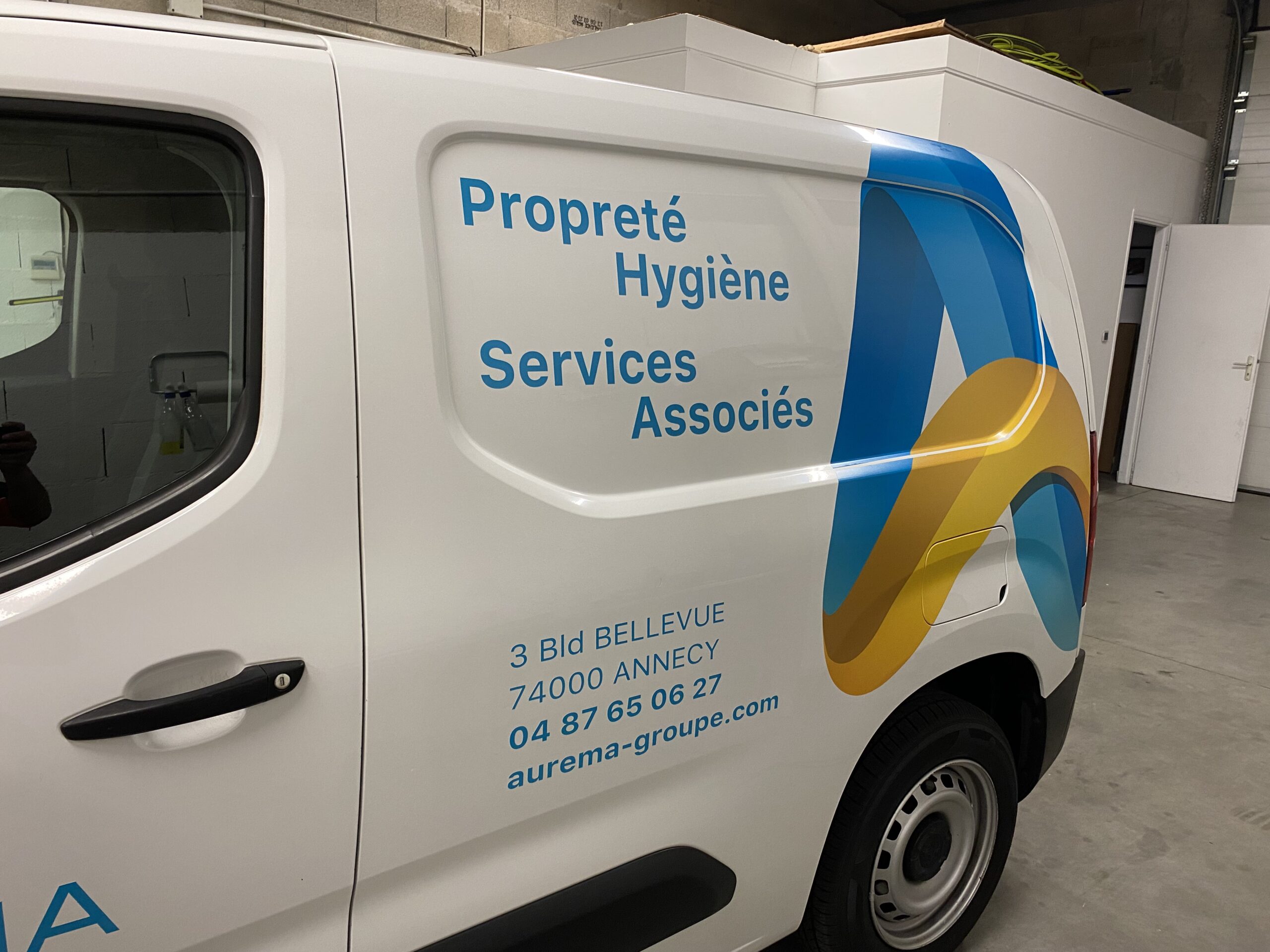 Marquage du véhicule utilitaire vue sur la partie arrière du véhicule pour le professionnel AUREMA avec logo et domaine de l'entreprise