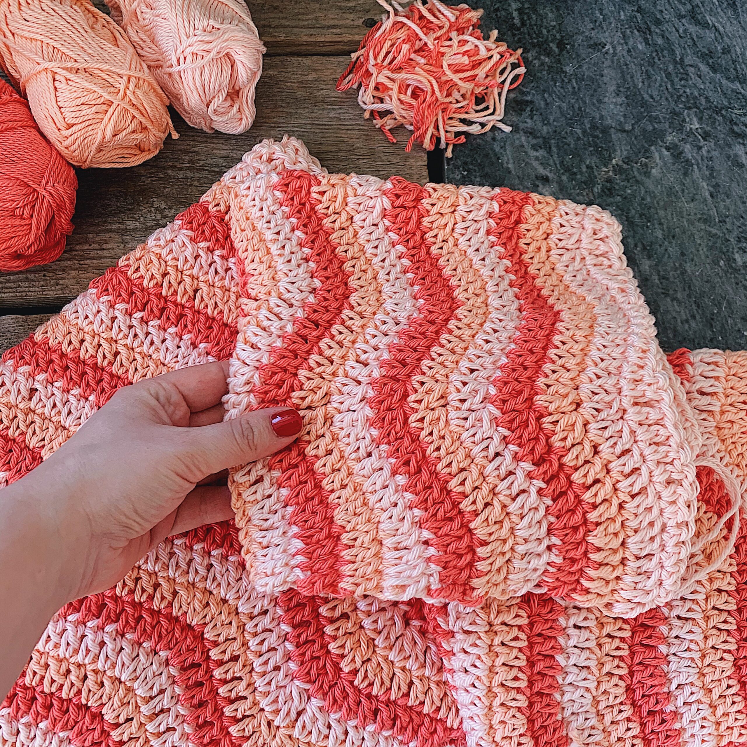 A closeup of the Malibu Sweater as a work in progress, pink and peachy shades in a wave pattern